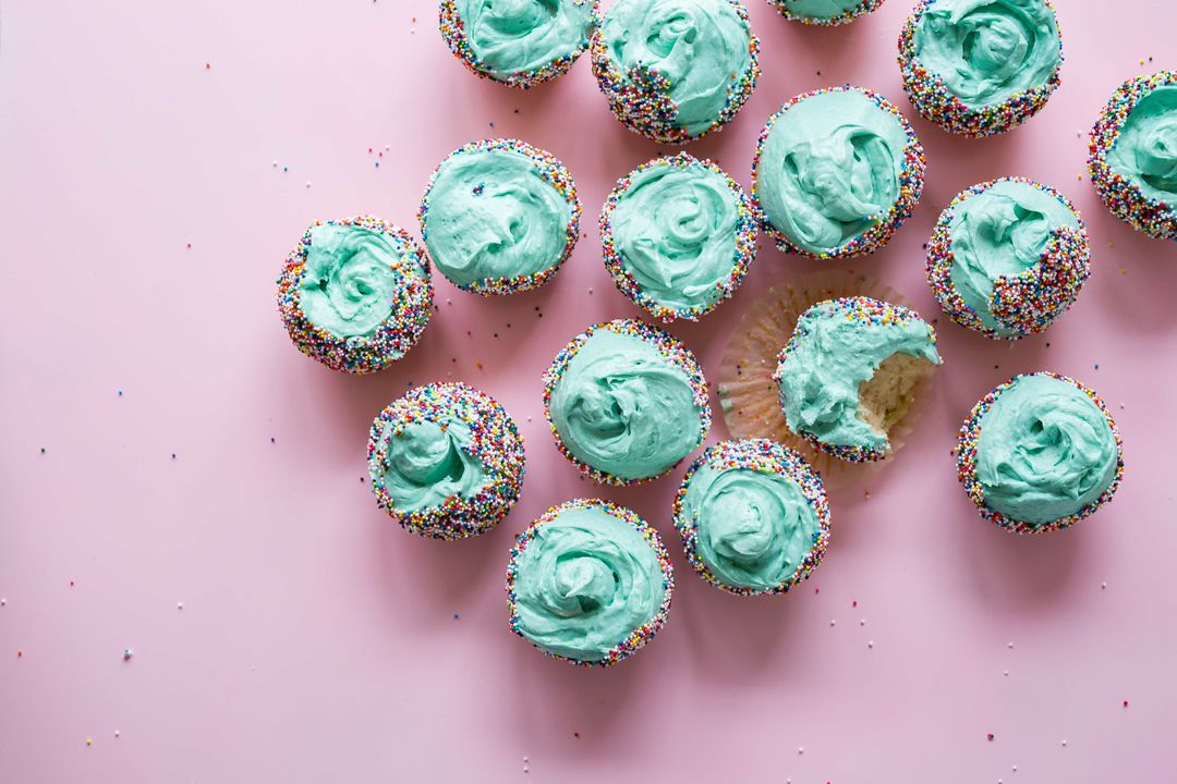 Colorful Cupcakes with Blue Icing and Sprinkles on Pink Surface