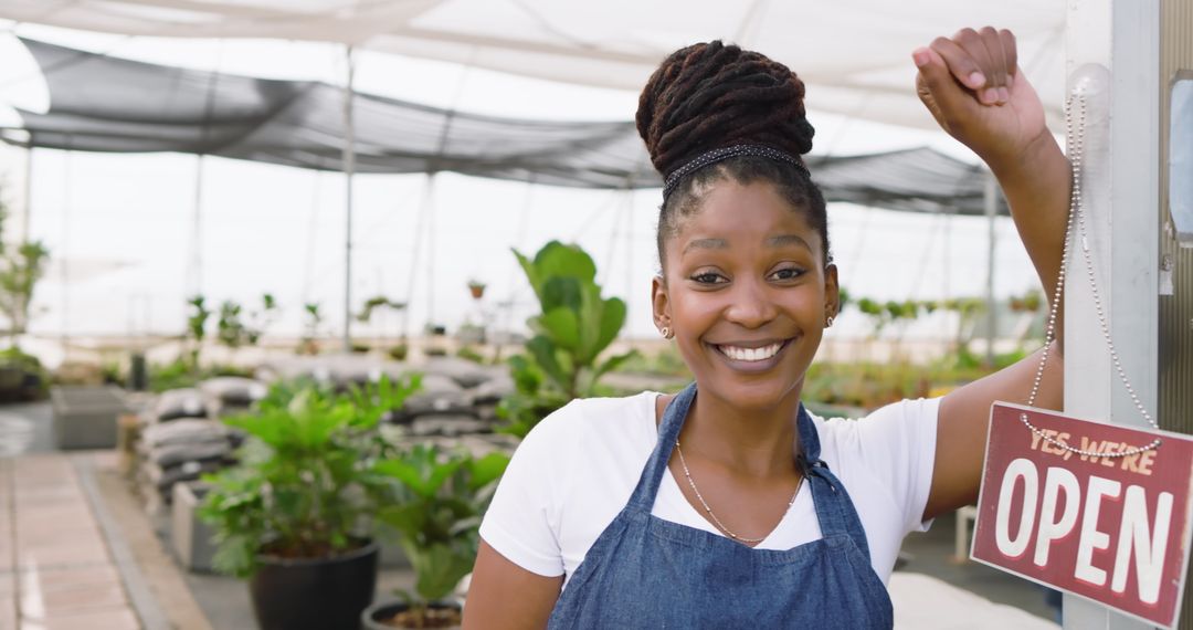 Smiling Gardener Holding Open Sign in Greenhouse