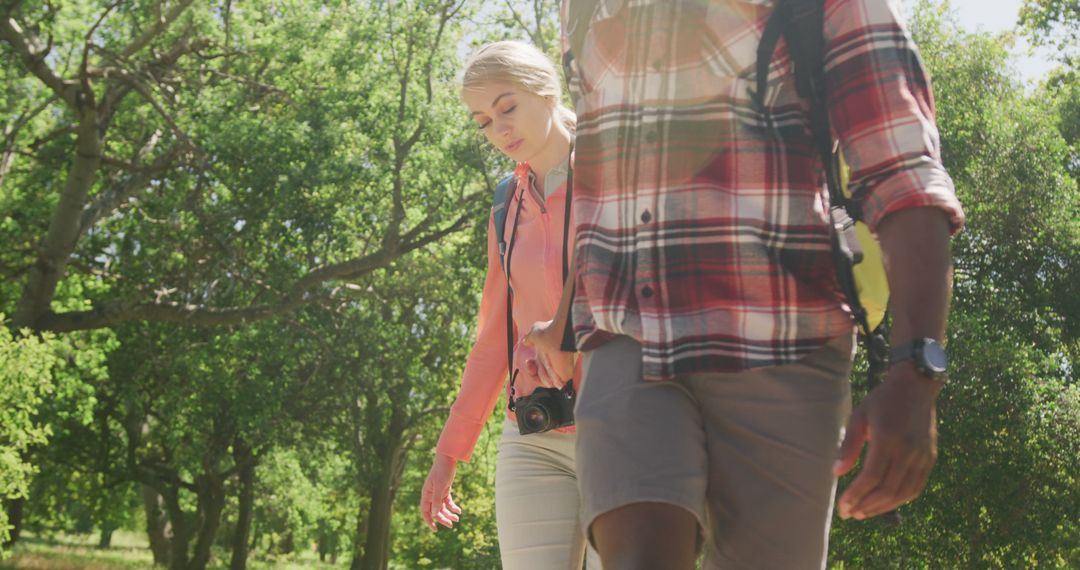 Couple Enjoying Nature Hike with Backpacks in Sunlit Forest
