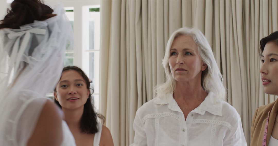 Bride Adjusting Veil with Family Helping in Wedding Preparation Indoor