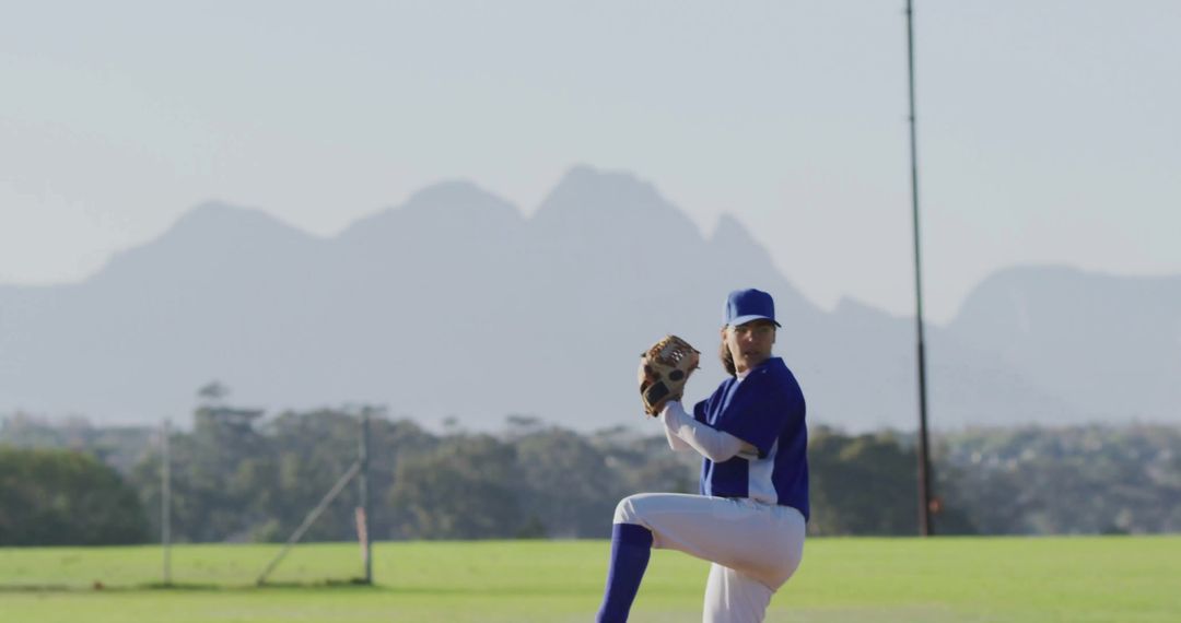 Baseball Pitcher in Action on Sunny Field Against Mountainous Backdrop