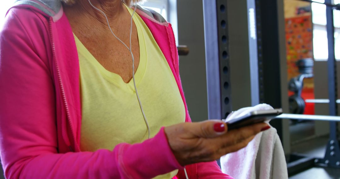 Mature woman using smartphone while working out at gym - Free Images, Stock Photos and Pictures on Pikwizard.com