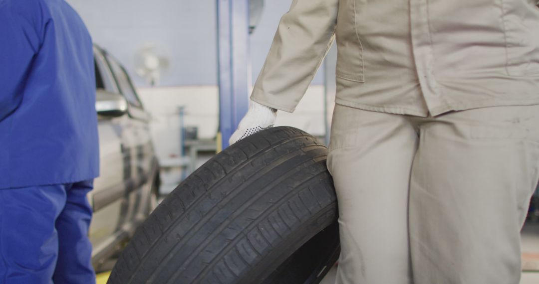 Auto Mechanic Carrying Tire in Repair Shop - Free Images, Stock Photos and Pictures on Pikwizard.com