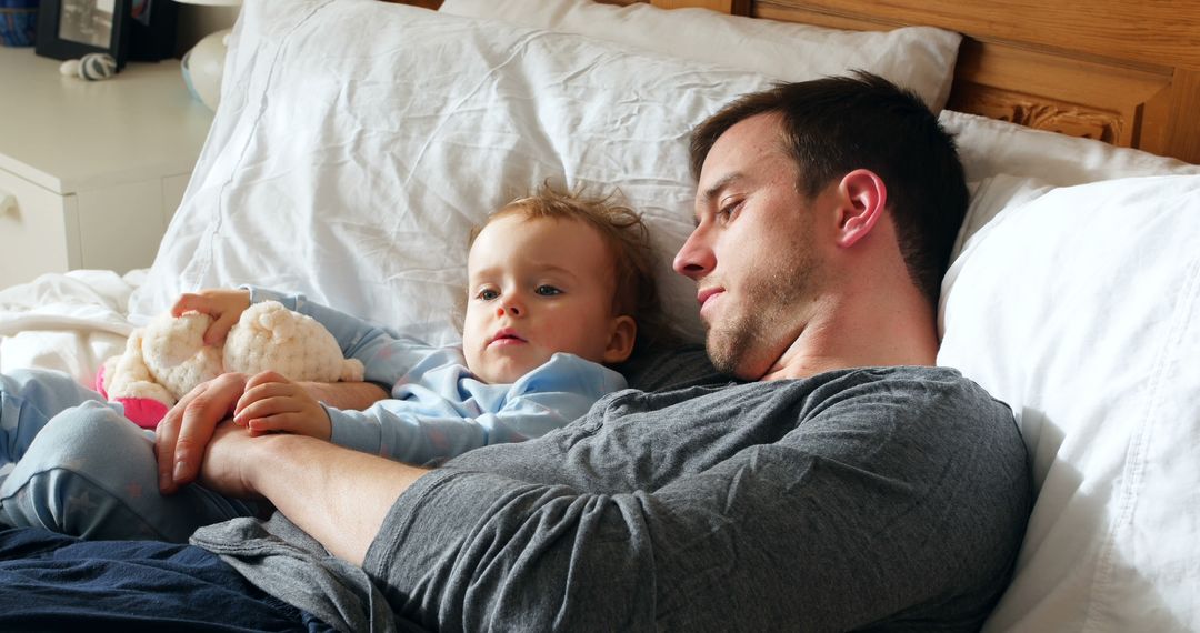 Father and Child Relaxing Together on Bed Cuddling with Toy