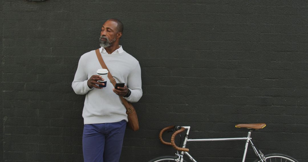 Stylish Mature Man with Coffee and Bicycle Against Black Wall - Free Images, Stock Photos and Pictures on Pikwizard.com