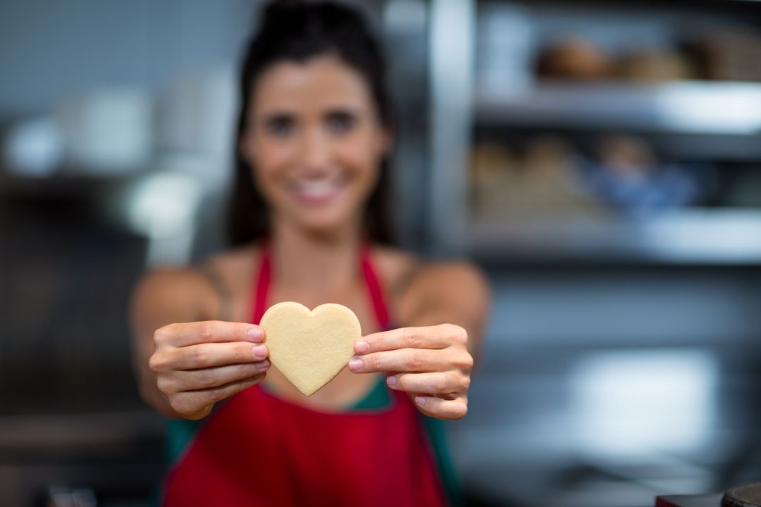Close-up of female staff showing heart shape cookie at counter - Free Images, Stock Photos and Pictures on Pikwizard.com