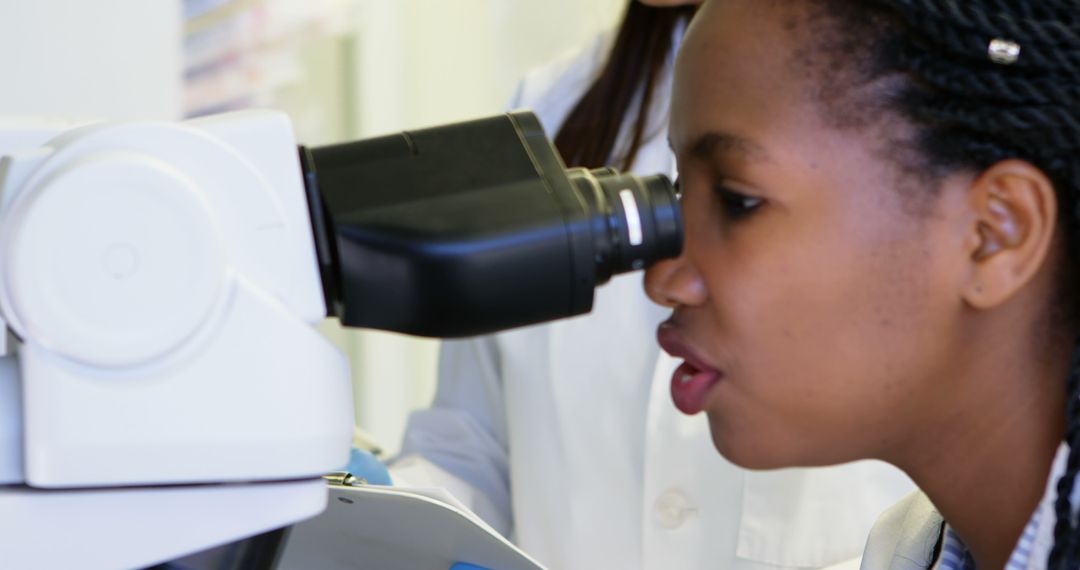 African American Female Scientist Looking Through Microscope in Laboratory - Free Images, Stock Photos and Pictures on Pikwizard.com