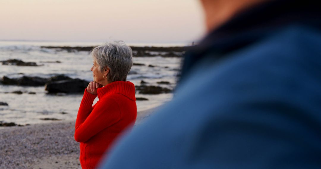 Contemplative Senior Woman on Rocky Shore at Sunset - Free Images, Stock Photos and Pictures on Pikwizard.com