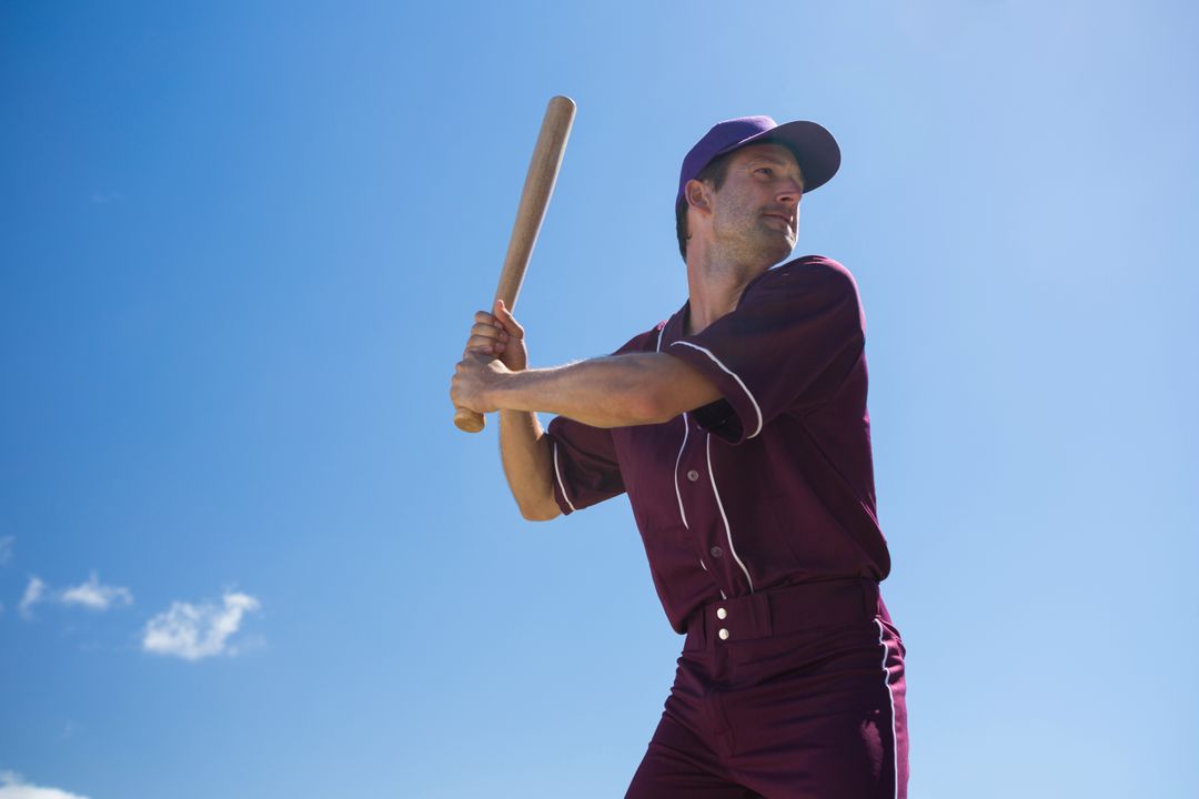 Low angle view of young baseball player holding bat against blue sky - Free Images, Stock Photos and Pictures on Pikwizard.com