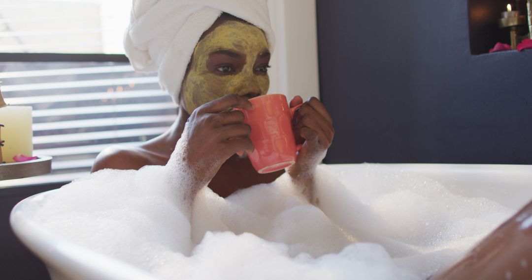 Smiling african american woman with towel and mask taking bath and drinking coffee in bathroom - Free Images, Stock Photos and Pictures on Pikwizard.com
