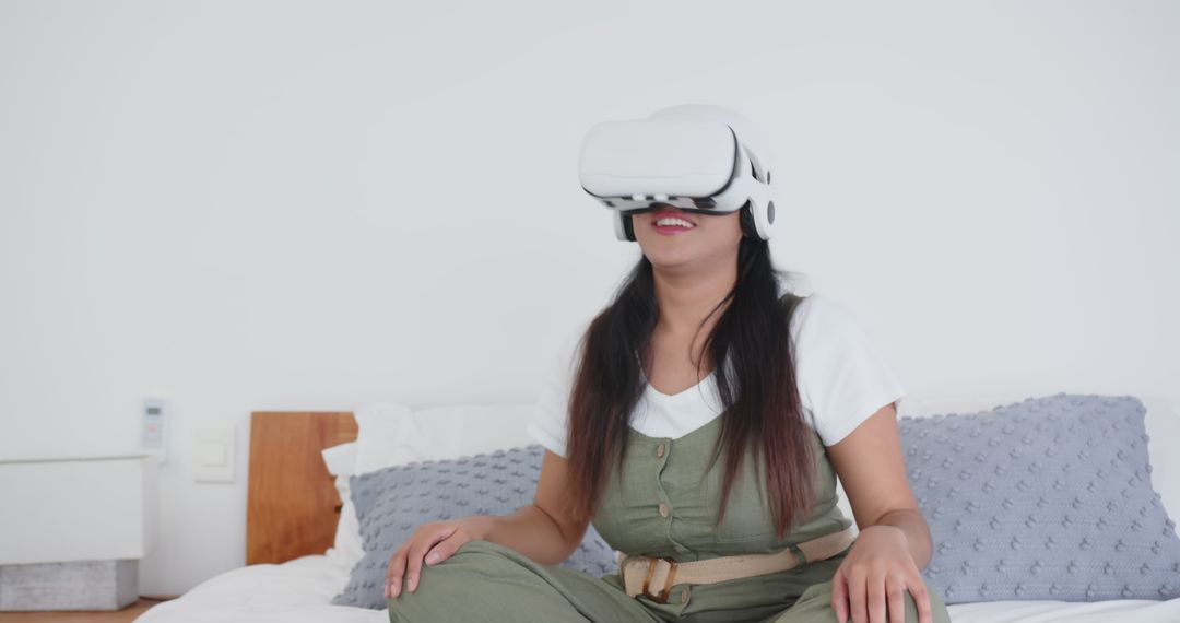 Woman Sitting Cross-Legged on Bed Using VR Headset for Virtual Exploration