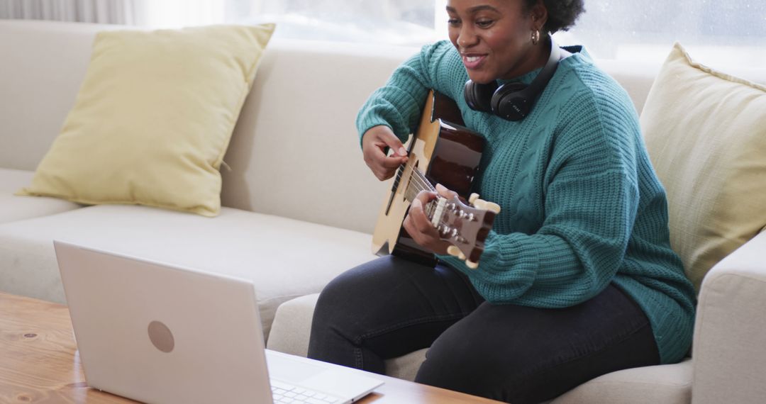 Woman Learning Guitar Online with Laptop from Living Room Sofa - Free Images, Stock Photos and Pictures on Pikwizard.com