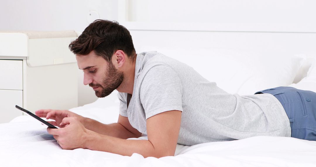 Man using tablet computer in bright modern bedroom - Free Images, Stock Photos and Pictures on Pikwizard.com