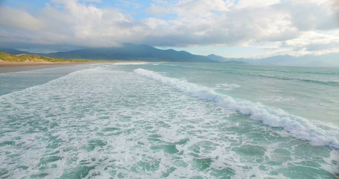 Tranquil Beach Waves with Majestic Mountain Backdrop - Free Images, Stock Photos and Pictures on Pikwizard.com