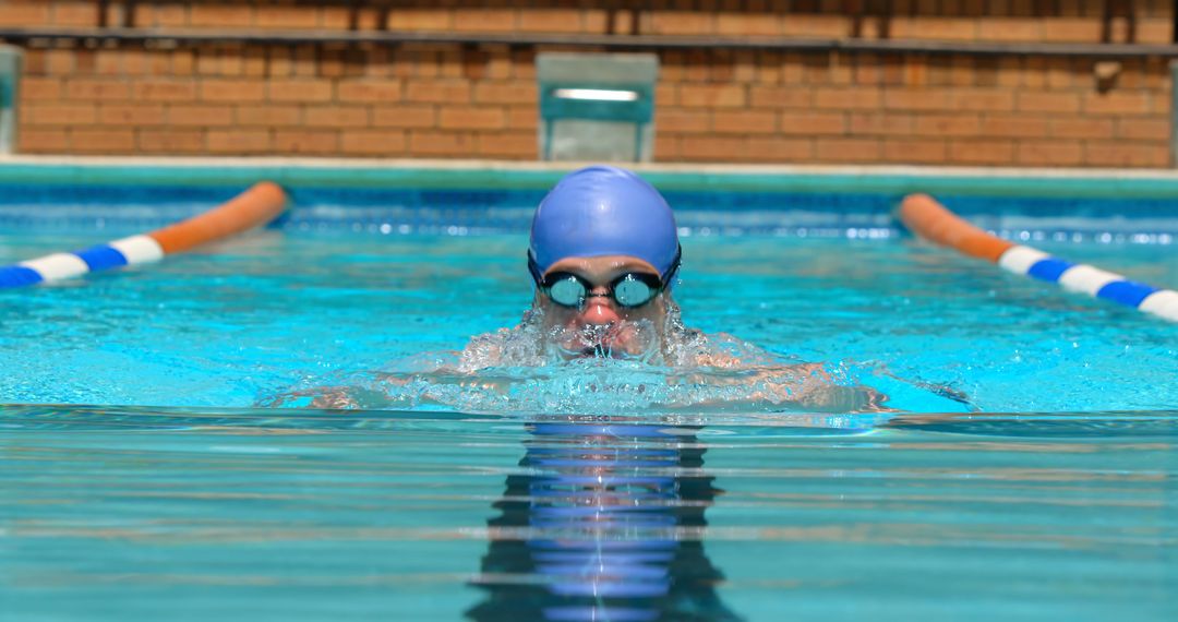 Swimmer Wearing Blue Cap and Goggles Practicing in Outdoor Pool - Free Images, Stock Photos and Pictures on Pikwizard.com