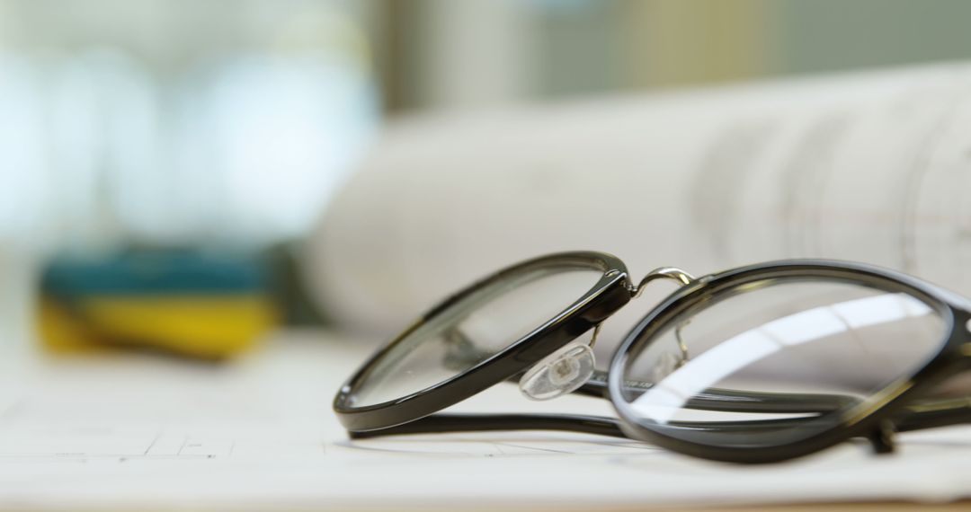 Close-Up of Black Glasses on Desk with Open Blueprint - Free Images, Stock Photos and Pictures on Pikwizard.com