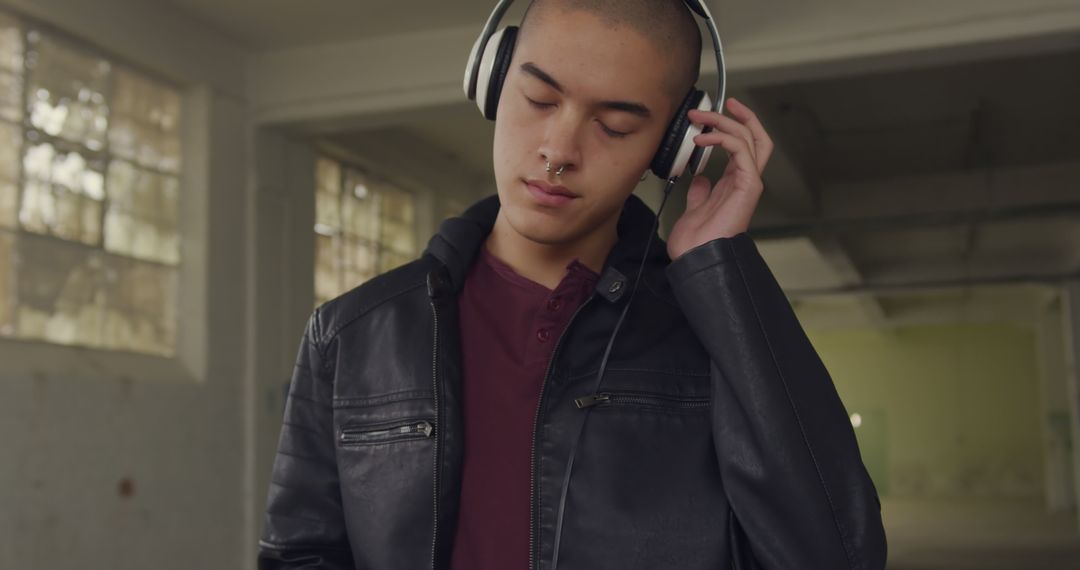 Young Man with Headphones Listening to Music in Abandoned Warehouse - Free Images, Stock Photos and Pictures on Pikwizard.com