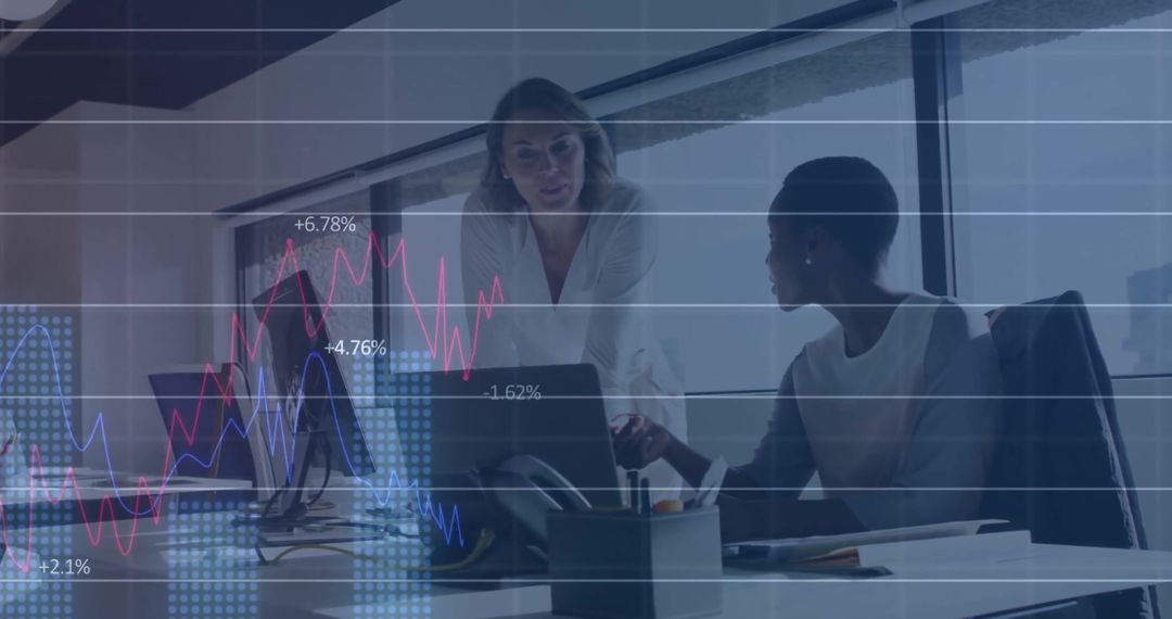 Diverse Businesswomen Analyzing Data with Financial Graph Overlay