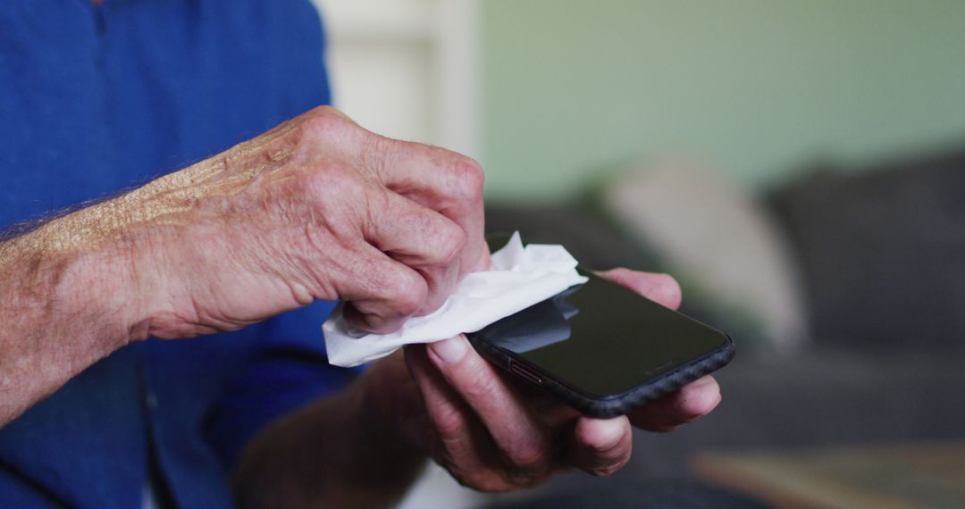 Person cleaning smartphone with disinfectant wipe at home - Free Images, Stock Photos and Pictures on Pikwizard.com