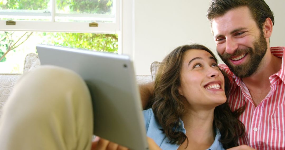 Happy Couple Relaxing on Couch Sharing a Tablet