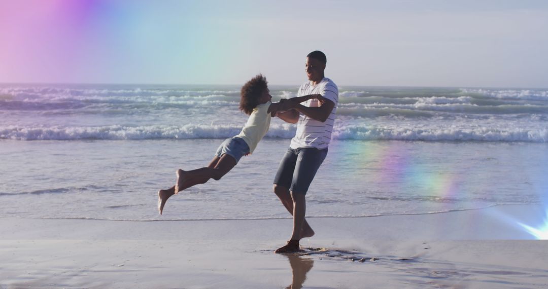 Father and Daughter Playing on Beach with Rainbow Light