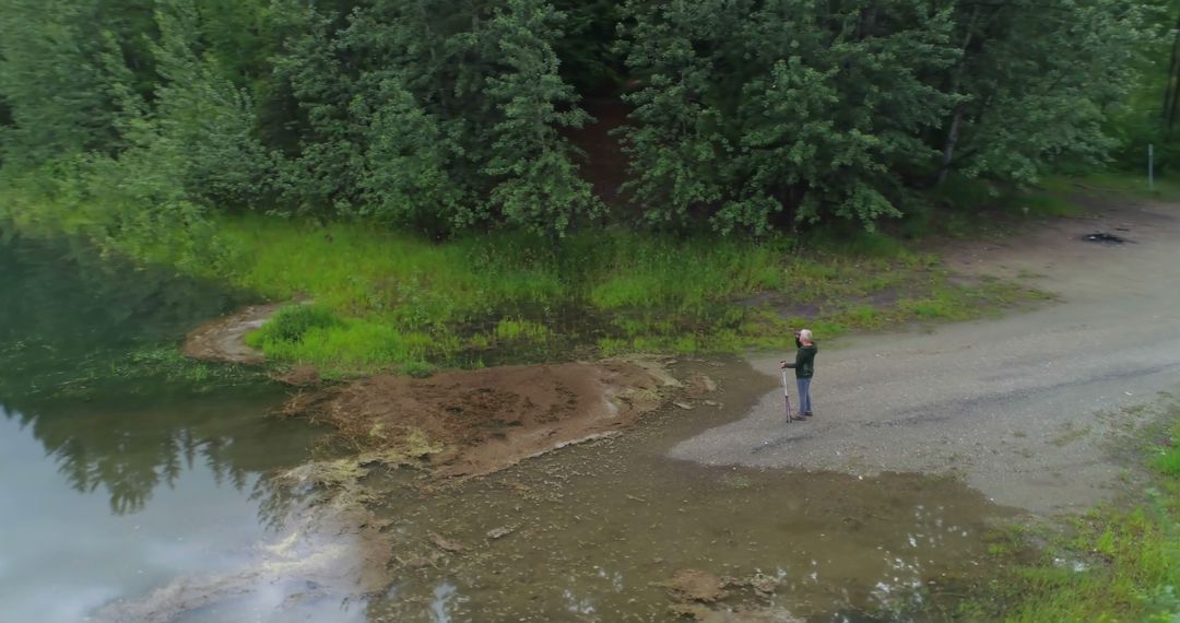 Drone View of Lone Fisherman at Peaceful Lakeshore - Free Images, Stock Photos and Pictures on Pikwizard.com