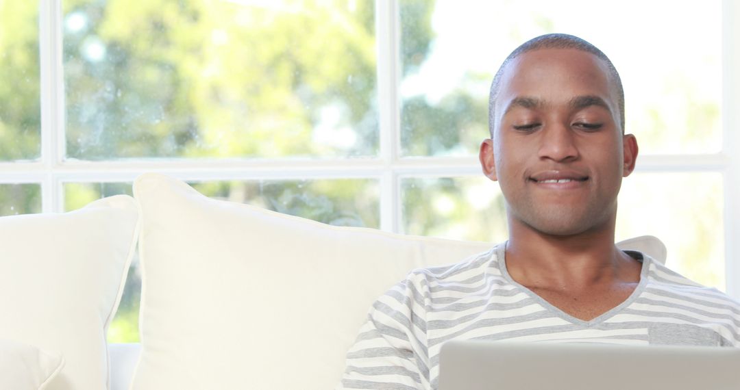 Young Man Using Laptop on Sofa, Relaxed Home Environment - Free Images, Stock Photos and Pictures on Pikwizard.com