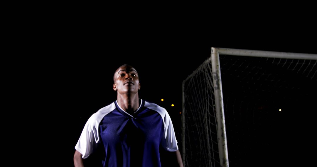 Confident Soccer Player Under Night Sky at Field
