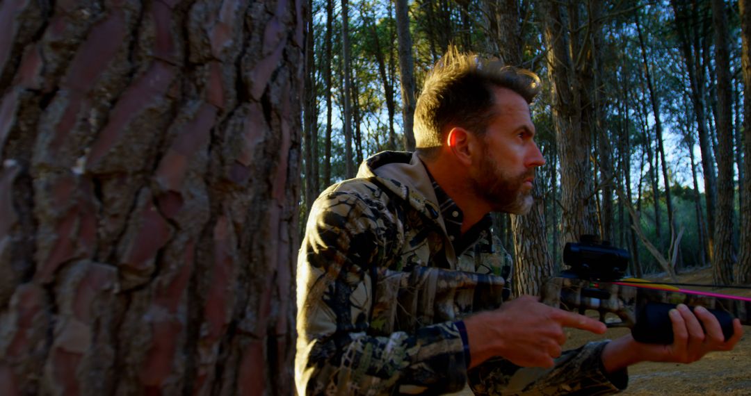 Camouflaged Hunter Aiming Bow in Forest at Sunset - Free Images, Stock Photos and Pictures on Pikwizard.com