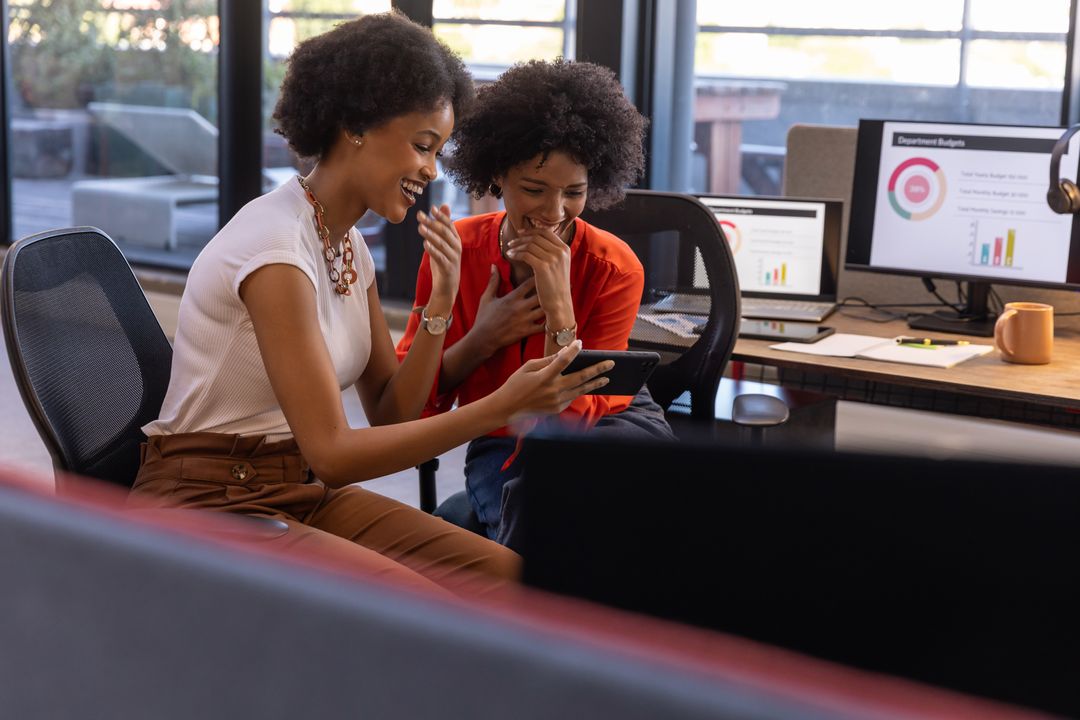 Diverse Female Colleagues Using Tablet in Modern Office