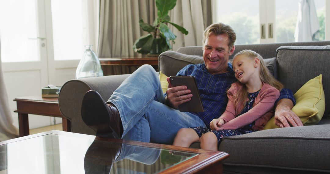 Father and Daughter Relaxing Together on Sofa Using Tablet - Free Images, Stock Photos and Pictures on Pikwizard.com