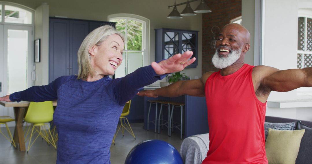 Biracial senior couple performing stretching exercise together at home - Free Images, Stock Photos and Pictures on Pikwizard.com