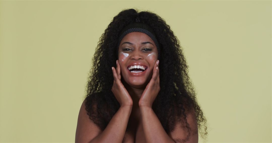 Joyful Black Woman Enjoying Skincare Routine with Headband
