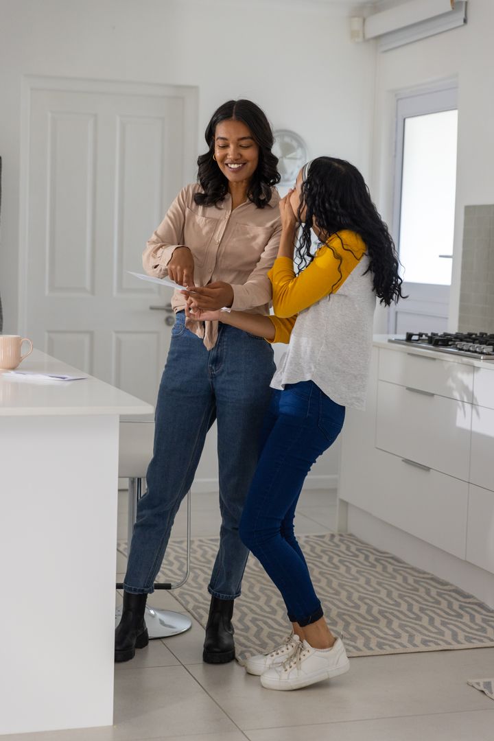 Mother and Daughter Discussing Papers in Modern Kitchen
