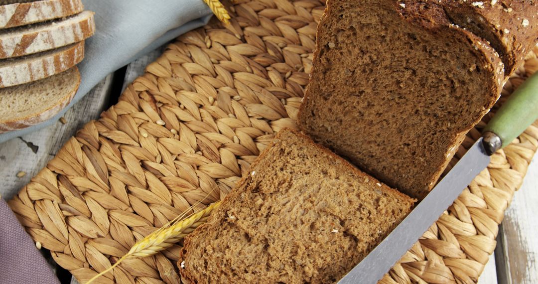 Freshly Baked Whole Grain Bread with Knife on Wicker Placemat - Free Images, Stock Photos and Pictures on Pikwizard.com