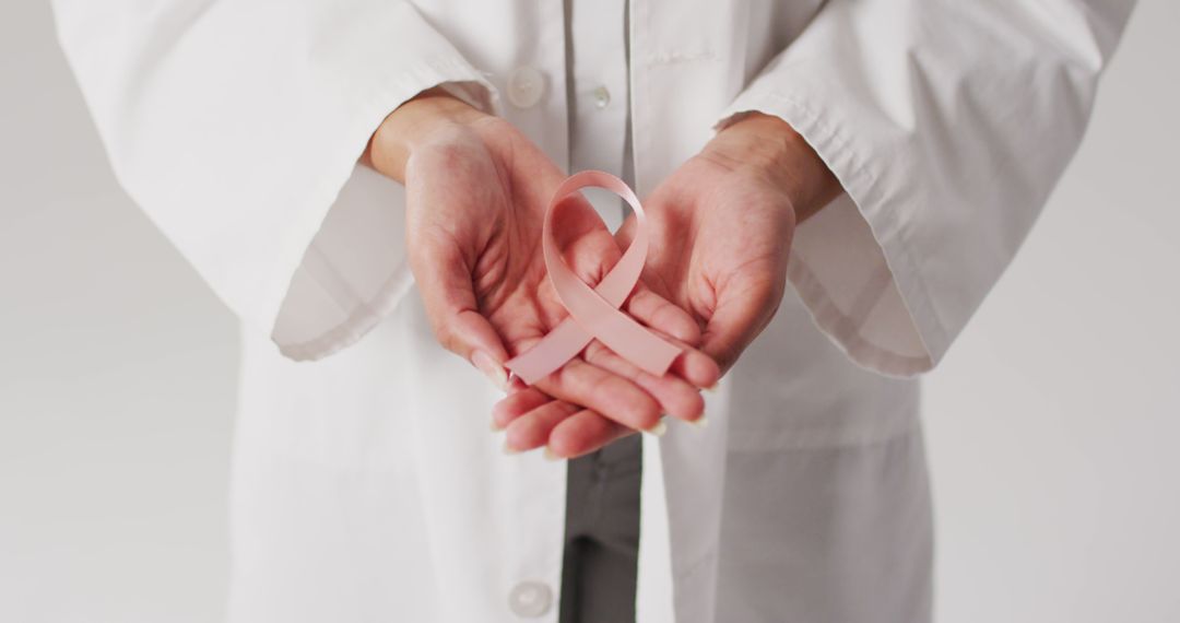 Image of biracial female doctor holding pink breast cancer ribbon - Free Images, Stock Photos and Pictures on Pikwizard.com