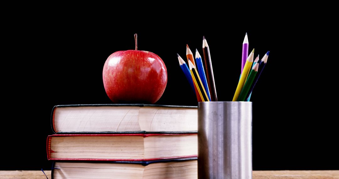 Stack of Books with Apple and Colorful Pencils in Holder Against Black Background - Free Images, Stock Photos and Pictures on Pikwizard.com