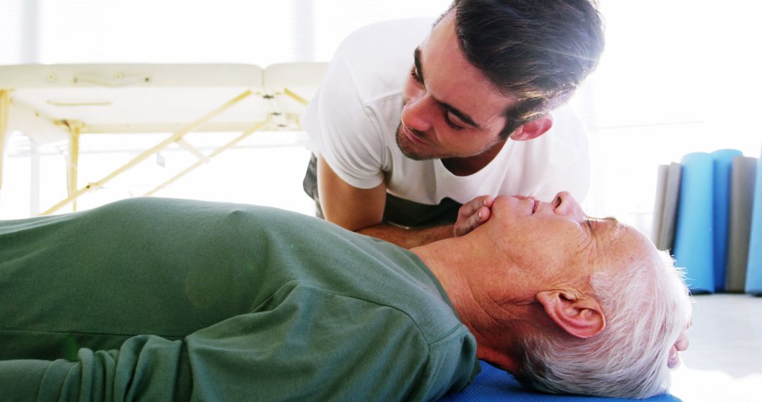 Young Man Checking Vital Signs of Elderly Man Lying on Floor in First Aid - Free Images, Stock Photos and Pictures on Pikwizard.com