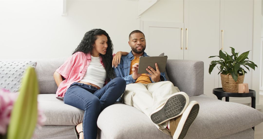 Pregnant Couple Relaxing on Couch at Home with Tablet