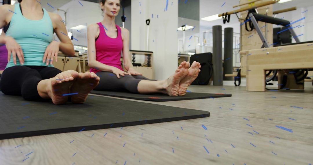 Two Women Stretching on Pilates Mats in Studio Practicing Flexibility and Core Mat Workout