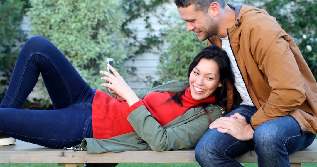 Young Couple Relaxing with Smartphone Outdoors, Enjoying Time Together