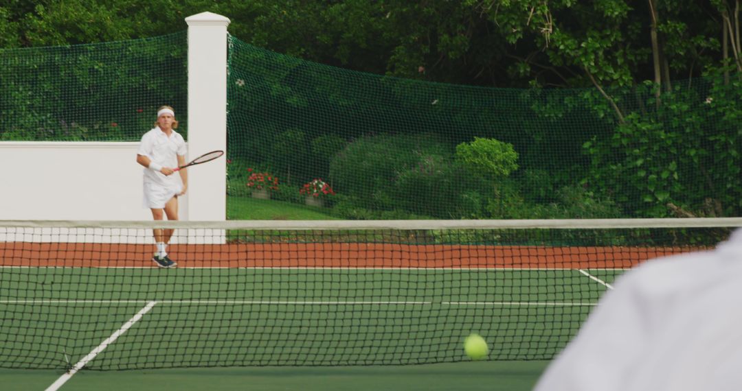 Senior playing tennis on outdoor court surrounded by greenery - Free Images, Stock Photos and Pictures on Pikwizard.com