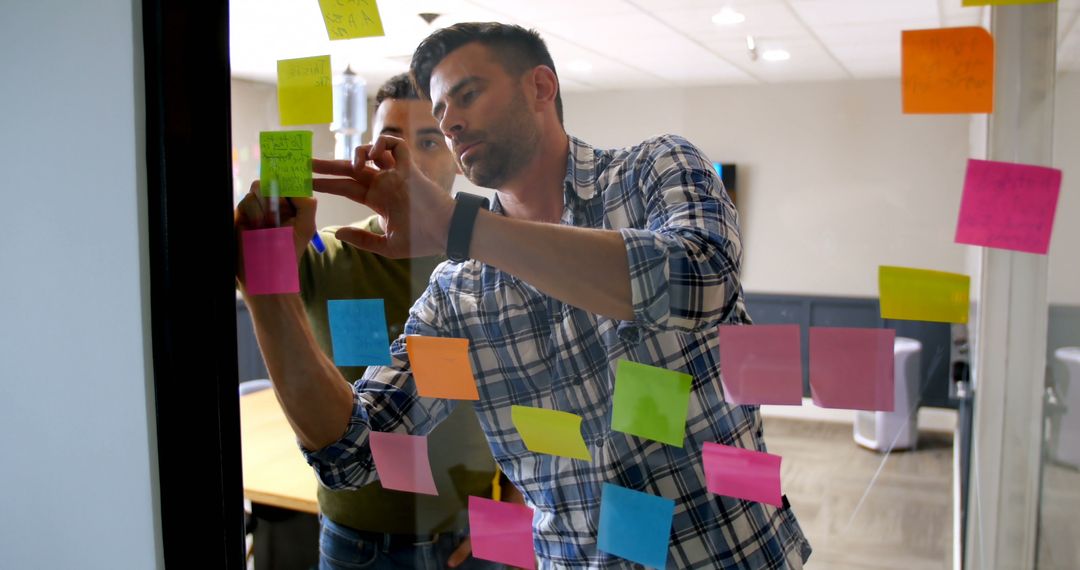 Two Professionals Collaborating with Sticky Notes on Glass Wall - Free Images, Stock Photos and Pictures on Pikwizard.com