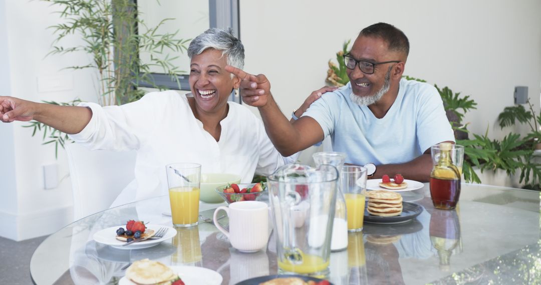 Smiling Couple Sharing Laughter Over Breakfast Table Indoors