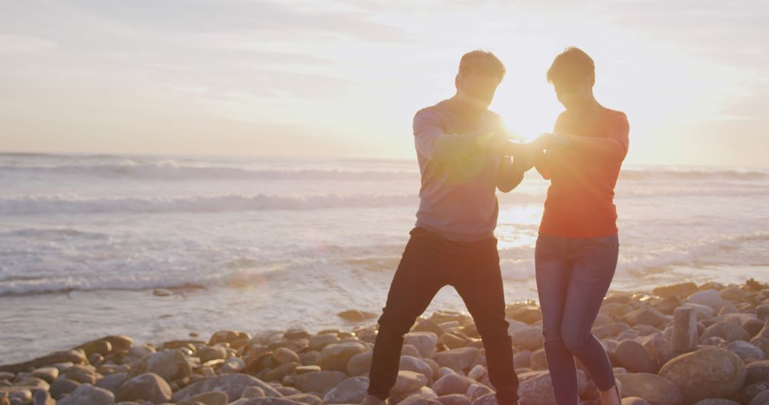 Couple Enjoying Sunset on Rocky Beach Shore - Free Images, Stock Photos and Pictures on Pikwizard.com