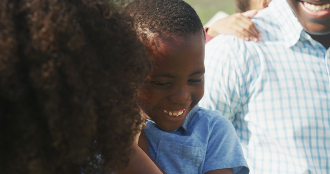 Smiling African American Boy Hugging Family Member Outdoors - Free Images, Stock Photos and Pictures on Pikwizard.com