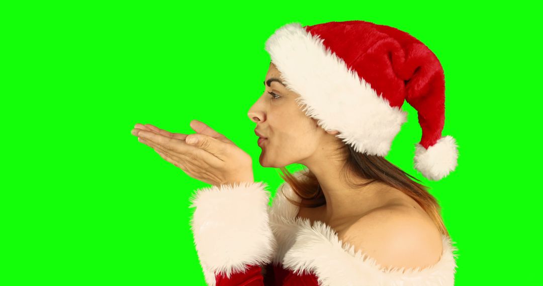 Festive Woman Blowing Kiss in Christmas Santa Hat on Green Background - Free Images, Stock Photos and Pictures on Pikwizard.com