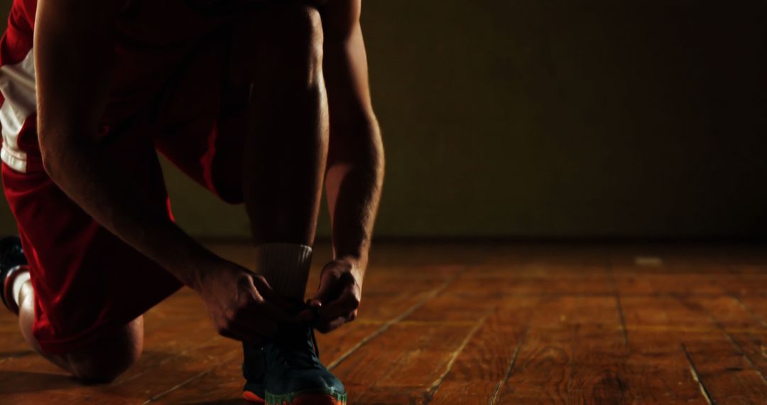 Athlete Tying Shoe Before Basketball Game on Wooden Court - Free Images, Stock Photos and Pictures on Pikwizard.com