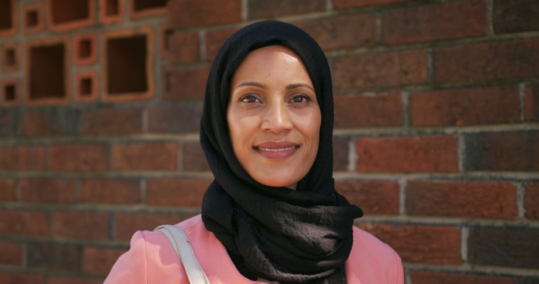 Portrait of happy casual businesswoman wearing hijab at brick wall on sunny day - Free Images, Stock Photos and Pictures on Pikwizard.com