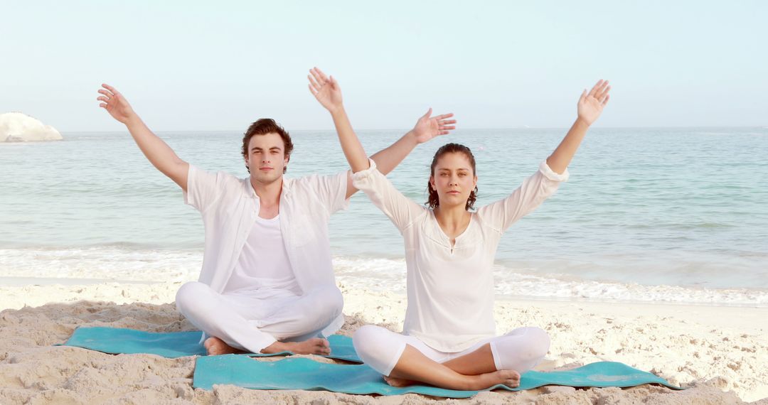 Couple Meditating on Beach with Arms Raised - Free Images, Stock Photos and Pictures on Pikwizard.com